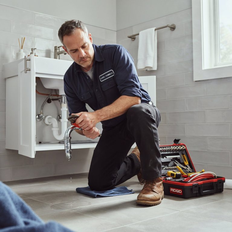 Plumber repairing a supply line under a vanity